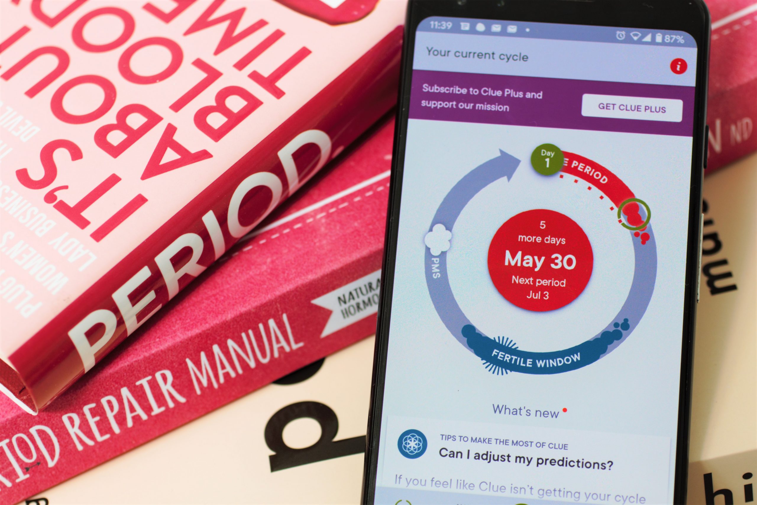 the best period tracking app - clue app shown resting against a pike of books about periods/ female health