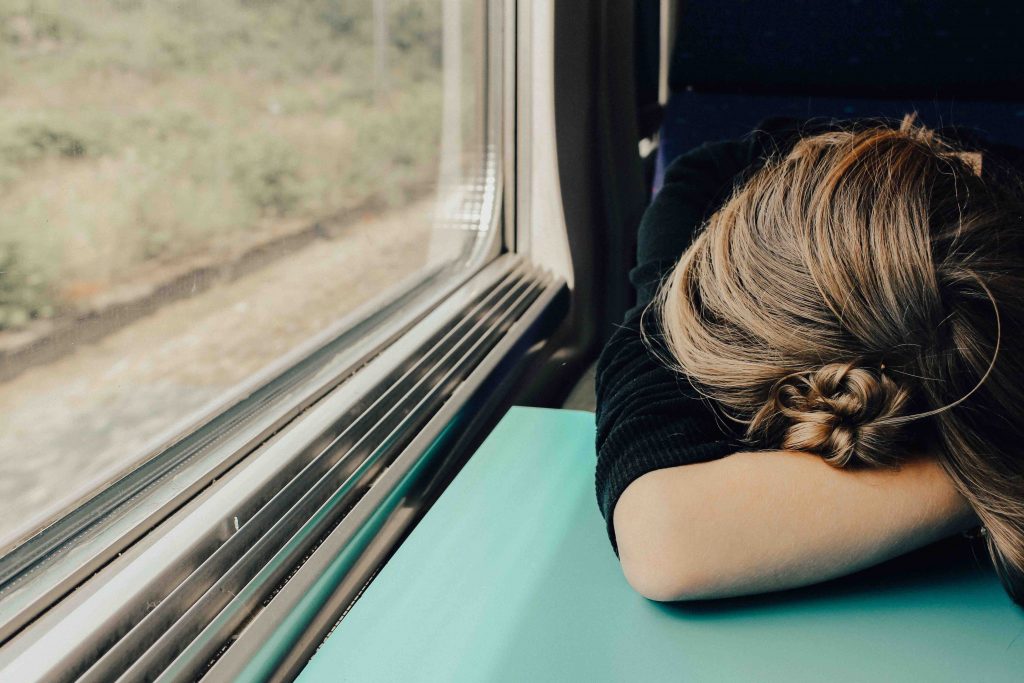 woman with her head down on a train taable, looking stressed